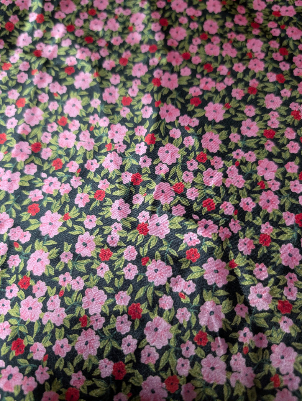 Floral fabric pattern with pink and red flowers on a dark background
