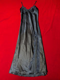A navy blue satin slip dress with lace trim and thin straps, laid flat on a bright red background.