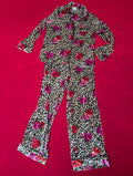 A two-piece pajama set featuring a long-sleeve button-up top and matching flared pants in a leopard print pattern with a vibrant pink and red floral print, laid flat on a bright red background.