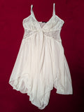 A white sheer babydoll nightgown with lace cups and thin shoulder straps, laid flat on a dark red background.
