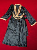 A navy blue satin-like robe or kimono-style garment laid flat on a bright red background, featuring gold trim along the collar and sleeve cuffs.