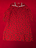 A red long-sleeve night dress with a dark floral pattern, laid flat on a solid red background. The dress features a white lace collar trim and buttons.